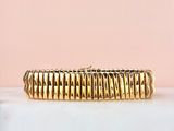 un gros plan d'un bracelet en or posé sur une surface en marbre