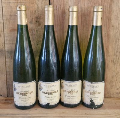 four bottles of wine are lined up on a wooden shelf