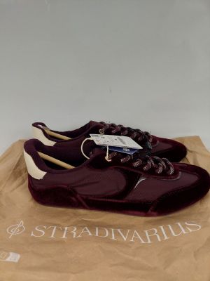 une paire de chaussures violettes posées sur un sac marron muni d'une étiquette