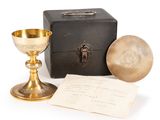 a gold chalicet next to a black box and a piece of paper