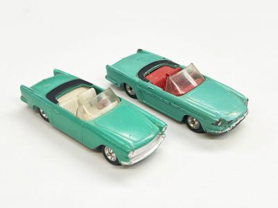 deux petites voitures vertes posées l'une à côté de l'autre sur une surface blanche