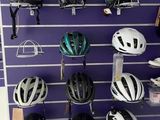 many helmets hanging on the wall of a bike shop