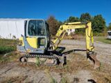 une petite pelleteuse jaune qui est à l'arrêt dans la terre