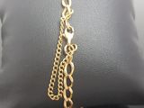 a close up of a gold chain bracelet on a pillow