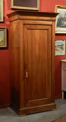 a tall wooden cabinet in a room with pictures on the wall