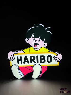 une photo d'une petite fille tenant une pancarte sur laquelle on peut lire « Haribo »