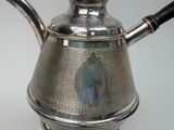a silver tea pot with a black handle on a table