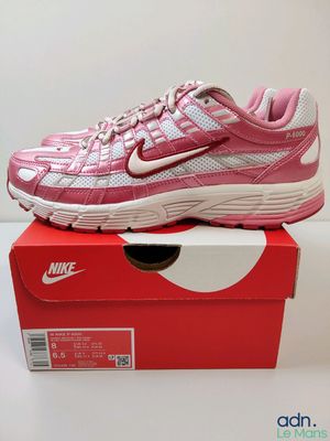 une chaussure de course Nike rose et blanche posée sur une boîte