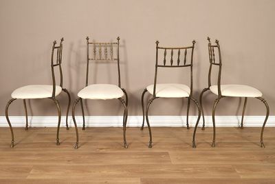 trois chaises en métal avec des coussins blancs sont adossées à un mur marron