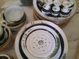 many plates and bowls on a table with a white table cloth