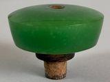 a green knob with a wooden base on a white surface