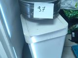 une poubelle posée sur une autre poubelle, à côté d'une autre poubelle
