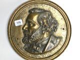 une image représentant un médaillon en bronze sur lequel figure le visage d'un homme