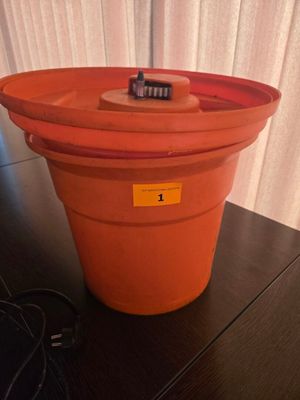un seau en plastique orange contenant une brosse à dents, posé sur une table