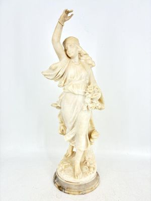 une statue ancienne représentant une femme tenant un oiseau dans la main