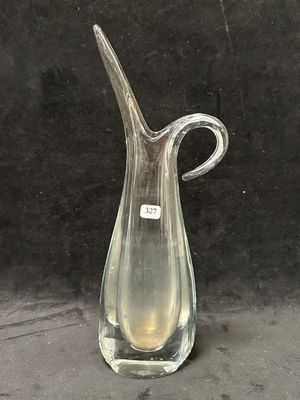 un vase en verre transparent muni d'une anse incurvée, posé sur une table