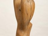 wooden sculpture of a hand holding a heart on a white pedestal