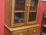 a wooden cabinet with glass doors and a rug on the floor