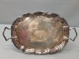 un plat ancien en argent avec des poignées, posé sur une table
