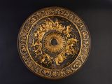 a gold plate with a clock on it on a black wall