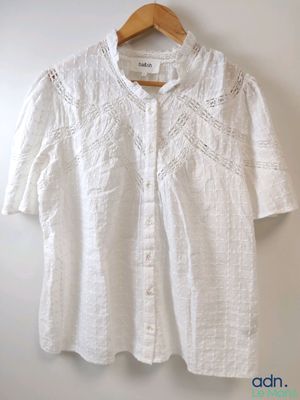 une chemise blanche suspendue à un mur à l'aide d'un cintre en bois