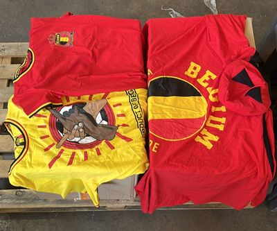 deux t-shirts rouges et jaunes posés sur une palette à côté d'une poubelle