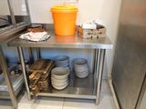 many plates and bowls on a stainless steel shelf in the kitchen