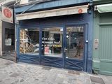 un immeuble bleu avec une vitrine donnant sur une rue pavée