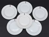 six assiettes plates blanches bordées d'or, disposées en cercle