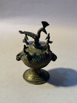 a small bronze vase with a bird on top of it