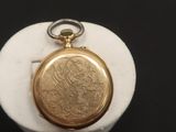une image représentant une montre de poche en or posée sur une assiette blanche