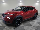 un SUV Nissan rouge garé sur un sol à damier dans un garage