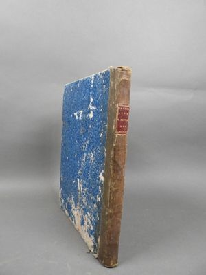 an old book with a blue cover sitting on a white surface