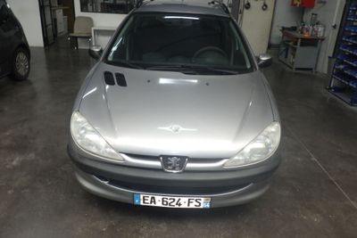 une voiture argentée garée dans un garage, avec d'autres voitures en arrière-plan