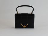 un sac à main noir avec une poignée dorée sur fond blanc