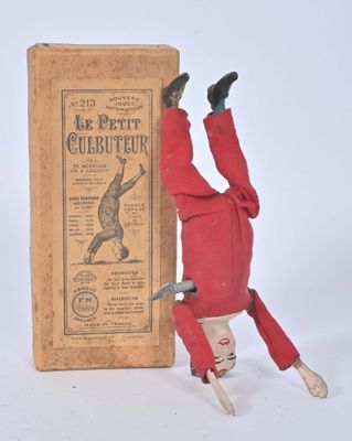 toy of a man upside down next to a book on a white surface