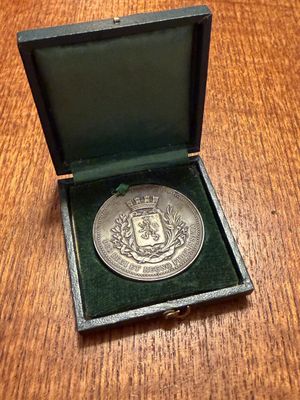 an old silver medal in a black box on a wooden table