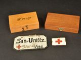 deux petites boîtes en bois et une petite boîte en bois sur laquelle est dessinée une croix rouge