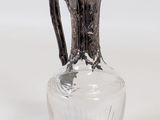 a glass vase with a silver handle on a white surface