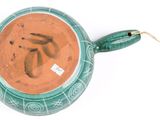a green pot with a handle on a white surface