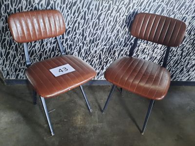 deux fauteuils en cuir marron placés l'un à côté de l'autre face à un mur