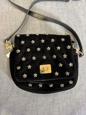 une photo d'un sac à main noir orné d'étoiles argentées