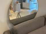 une photo d'un salon avec un canapé et un miroir rond
