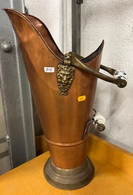 un vase en métal muni d'une anse, posé sur une table en bois