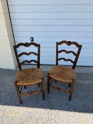 two wooden chairs sitting next to each other in front of a garage door