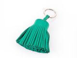 un porte-clés vert orné d'un pompon et muni d'un anneau métallique, sur fond blanc