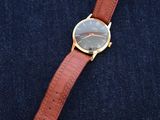 a close up of a watch sitting on top of a pair of jeans