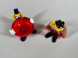 two figurines of a man and a woman sitting on top of a red ball