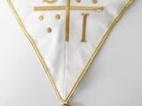 a close up of a cross on a white cloth with a gold cross