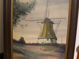 painting of a windmill in a frame on the floor next to a chair